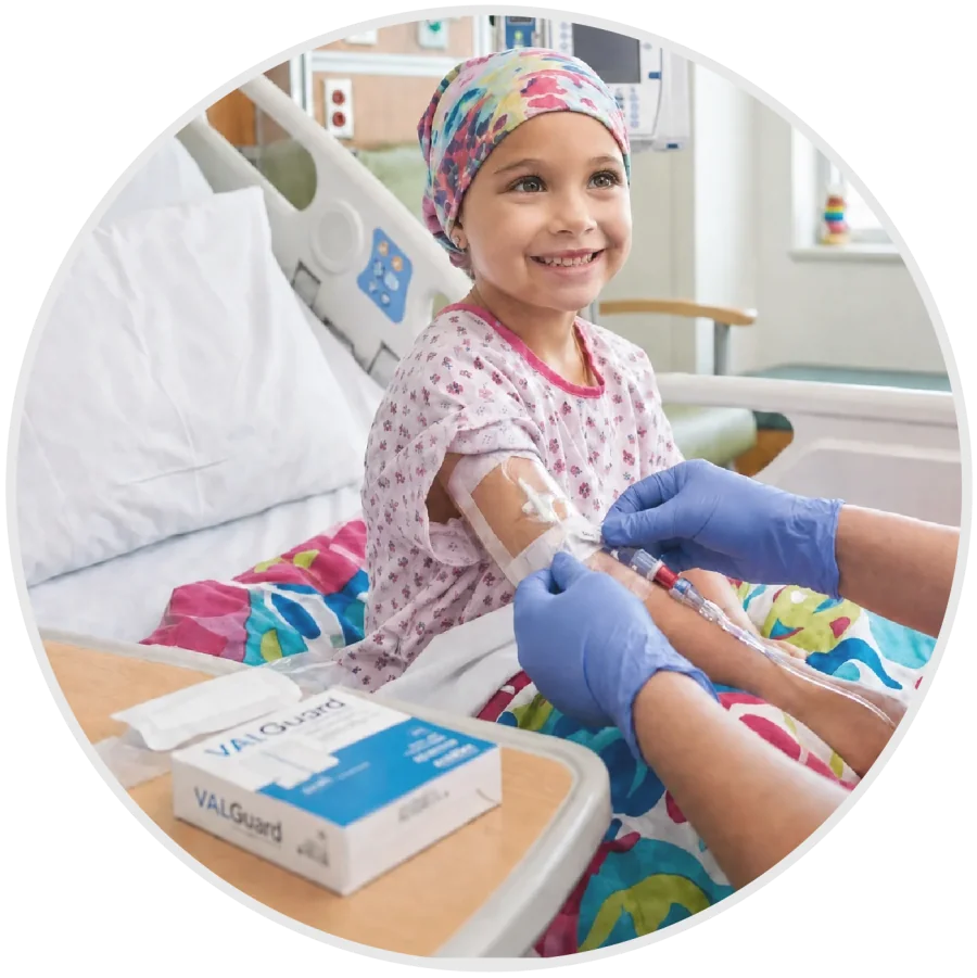 Nurse caring for a smiling child in a hospital bed, with a VALGuard box on the table